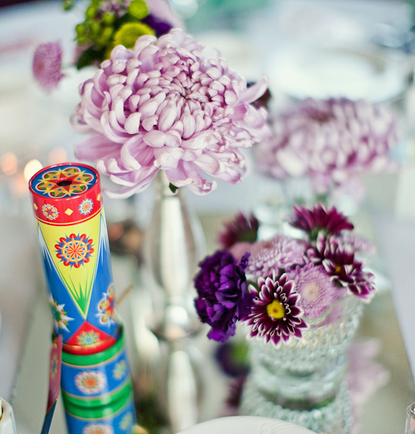 Reception tabletop decor - purple and lavender floral arrangements and a display of the wedding favor, a vivdly colorful kaleidescope - photo by Orange County based wedding photographers Mark Brooke